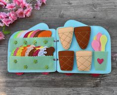 an ice cream sandwich decorated with felt on a wooden table next to pink flowers and leaves