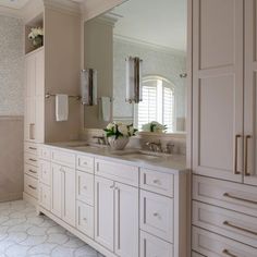 a large bathroom with two sinks and mirrors on the wall, along with white cabinetry