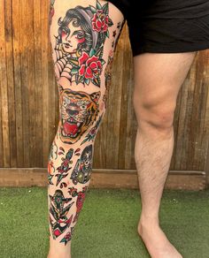 a man with tattoos on his legs and leg is standing in front of a wooden fence