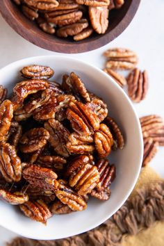 two white bowls filled with pecans on top of a table next to each other