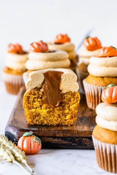 cupcakes with frosting and pumpkin decorations on a cutting board