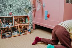 a doll house is sitting on the floor in front of a pink dresser and chair