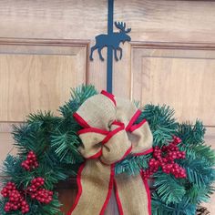 a christmas wreath hanging on a door with red and green berries, pine cones and a deer