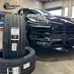 two tires are stacked on top of each other in front of a black sports car