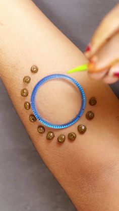 a woman is holding a toothbrush and some brown dots on her arm with a blue ring around it