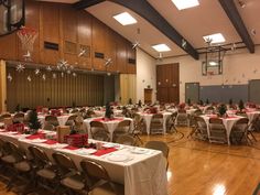 an indoor basketball court decorated for christmas with tables and chairs set up in the center