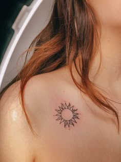 a woman's chest with a small sun tattoo on her left shoulder and right breast