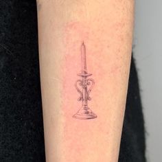 a small candle tattoo on the arm