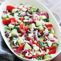 a salad with cucumbers, red onions and feta cheese in a white bowl