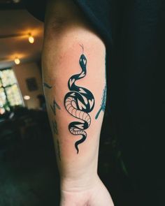 a black and white snake tattoo on the left arm by a person's hand