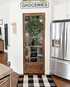 a kitchen with white walls and wood trimming on the door, has a black and white checkered rug in front of it