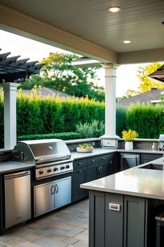 Outdoor kitchen with stainless steel appliances, surrounded by greenery and a pergola.