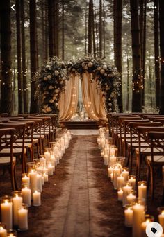 an outdoor wedding setup with candles and flowers on the aisle, surrounded by tall trees