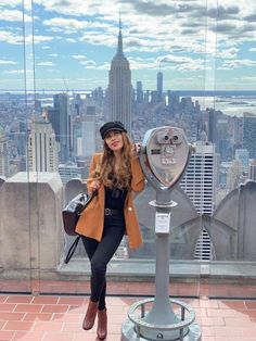 a woman standing in front of a coin meter on top of a building with the empire building in the background