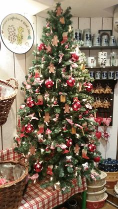 a decorated christmas tree in the corner of a room with baskets and other items around it