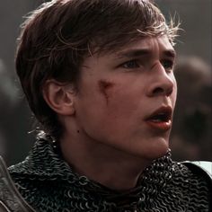 a young man in armor with blood on his face