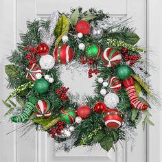 a christmas wreath is hanging on the front door, decorated with ornaments and greenery