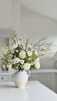 a white vase filled with flowers sitting on top of a kitchen counter next to an oven