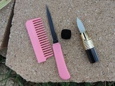 two pink combs sitting next to each other on top of a stone slab with a knife and brush