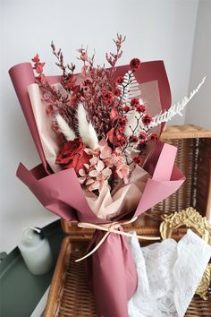 a bouquet of flowers is wrapped in pink paper and tied to a wicker basket