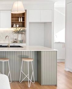 a kitchen with two stools next to an island