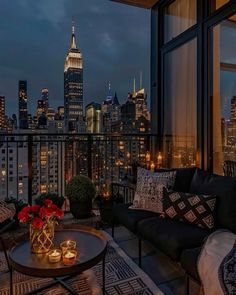 a living room filled with furniture and a view of the empire building at night in new york city