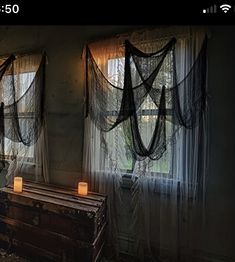 two windows with curtains and candles in them