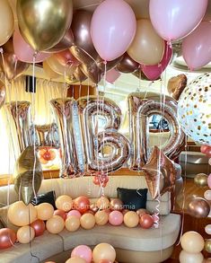 balloons are floating in the air above a couch and table with large letters on it