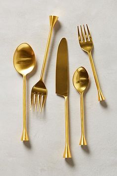 gold colored utensils and spoons laid out on a white surface