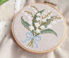 a close up of a cross stitch pattern on a white cloth with flowers in it