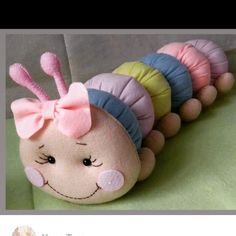 a stuffed caterpillar with a pink bow on it's head is shown