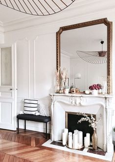 a living room with a fire place and mirror on the wall above it, along with candles