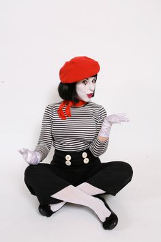 a woman dressed in black and white is sitting on the floor with her hands out