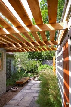 a wooden pergoline over a walkway next to a building