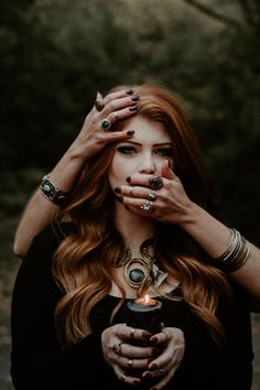 a woman with long red hair holding her hands up to her face and looking at the camera