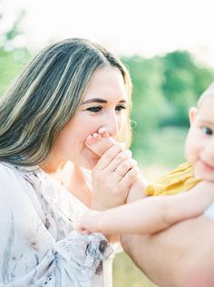 a woman holding a small child in her arms while she holds the baby's hand