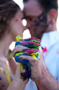 a man and woman kissing while covered in colored powder with their hands on each other