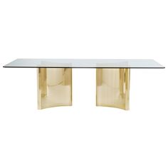 a glass and brass dining table with two curved legs, viewed from the front view