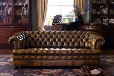 a brown leather couch sitting in front of a window