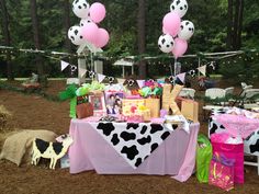 a table topped with lots of pink and white balloons next to a cow print table cloth