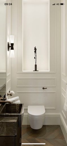 a white toilet sitting next to a sink in a bathroom under a window with lights