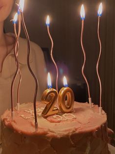 a woman standing in front of a cake with candles on it and the number twenty