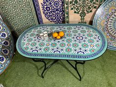 a table with two oranges sitting on top of it next to plates and vases