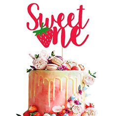 a strawberry cake with the word sweet one on top and flowers around it, sitting on a table