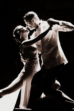 a man and woman dancing on stage in black and white photo with one arm around the other's waist