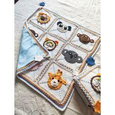 four crocheted squares with animals on them sitting on top of a white table cloth