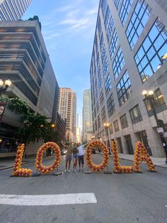 three people standing in the middle of an empty street with balloons spelling out'aloha '