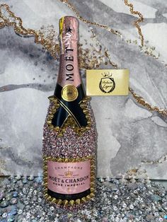 a bottle of champagne sitting on top of a table next to a gold and black tag