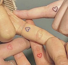 three fingers with hearts tattooed on them