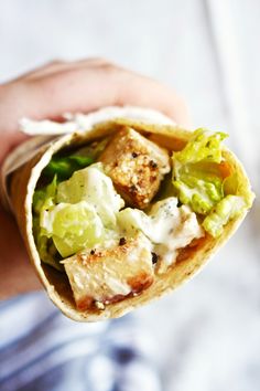 a person holding a wrap filled with meat and vegetables